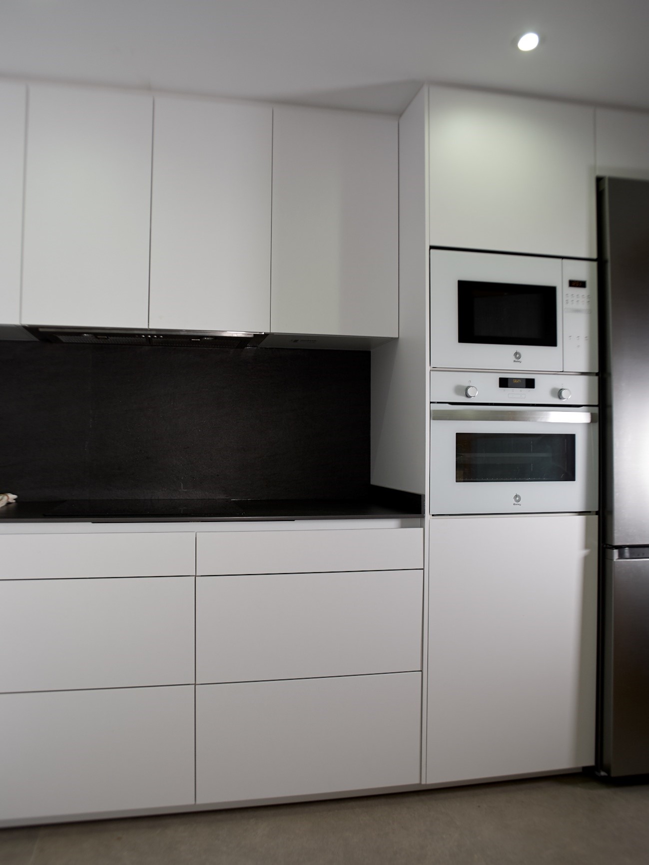 Imagen cocina blanco y negro con columna de microondas y horno 